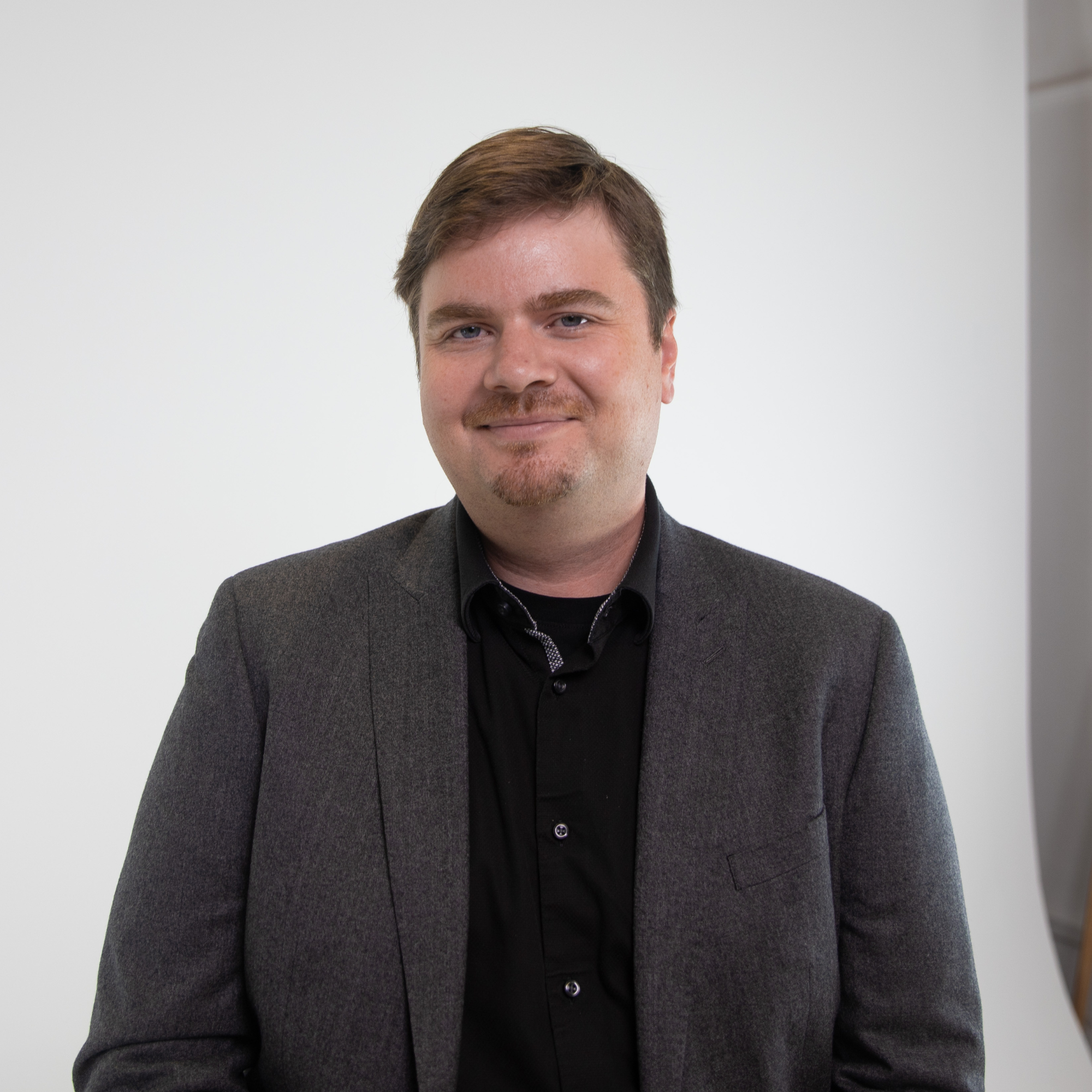 Associate Professor Brent Mittelstadt smiles into the camera against a white photography studio backdrop