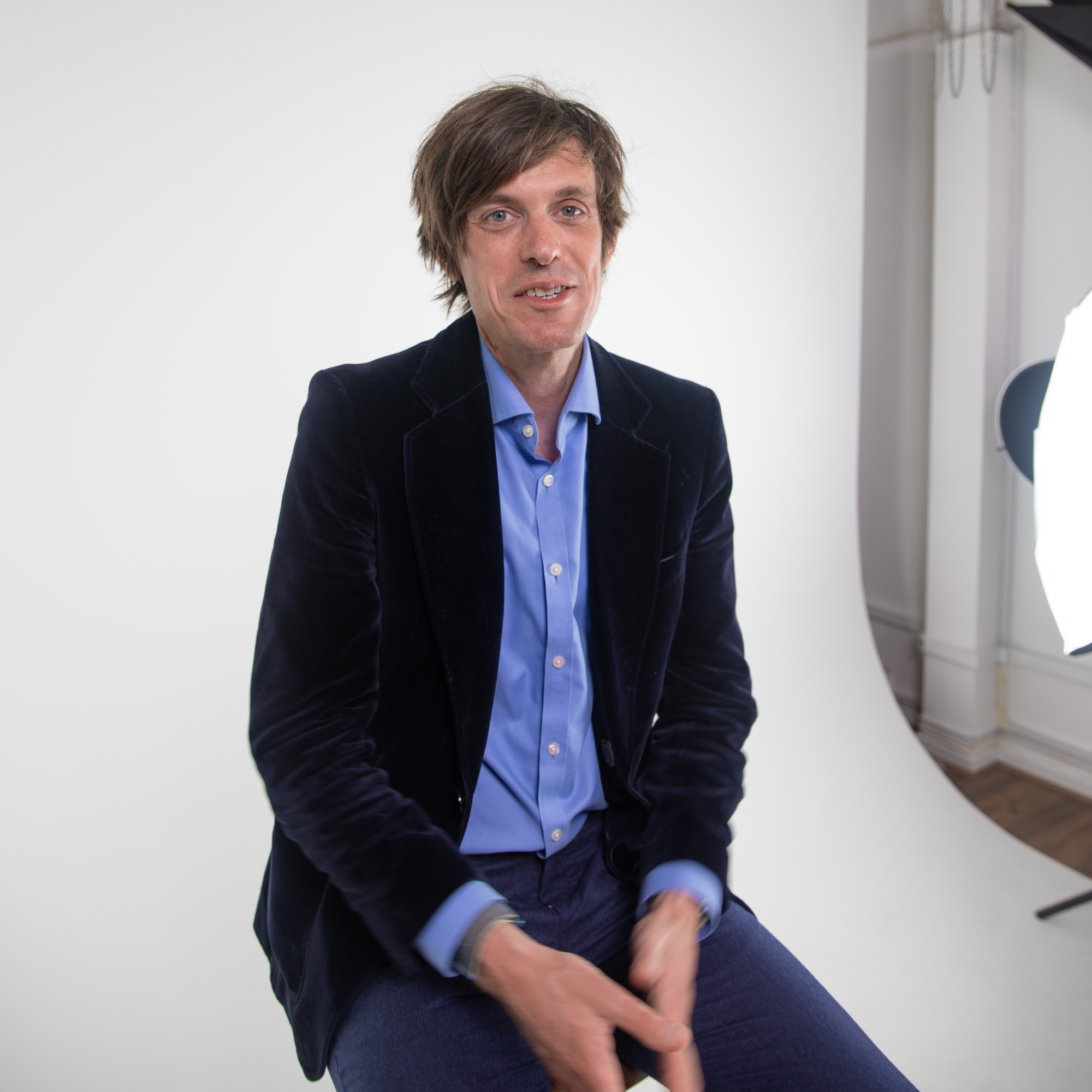 Professor Mike Osborne sits in a photography studio in front of a white backdrop