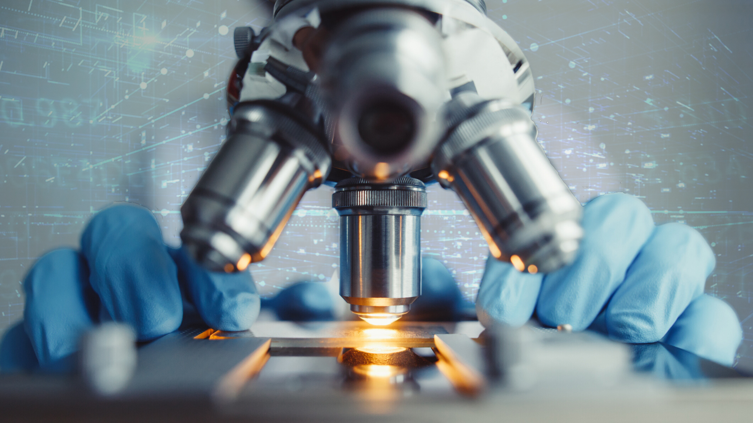 A scientist wearing blue gloves looks through a microscope