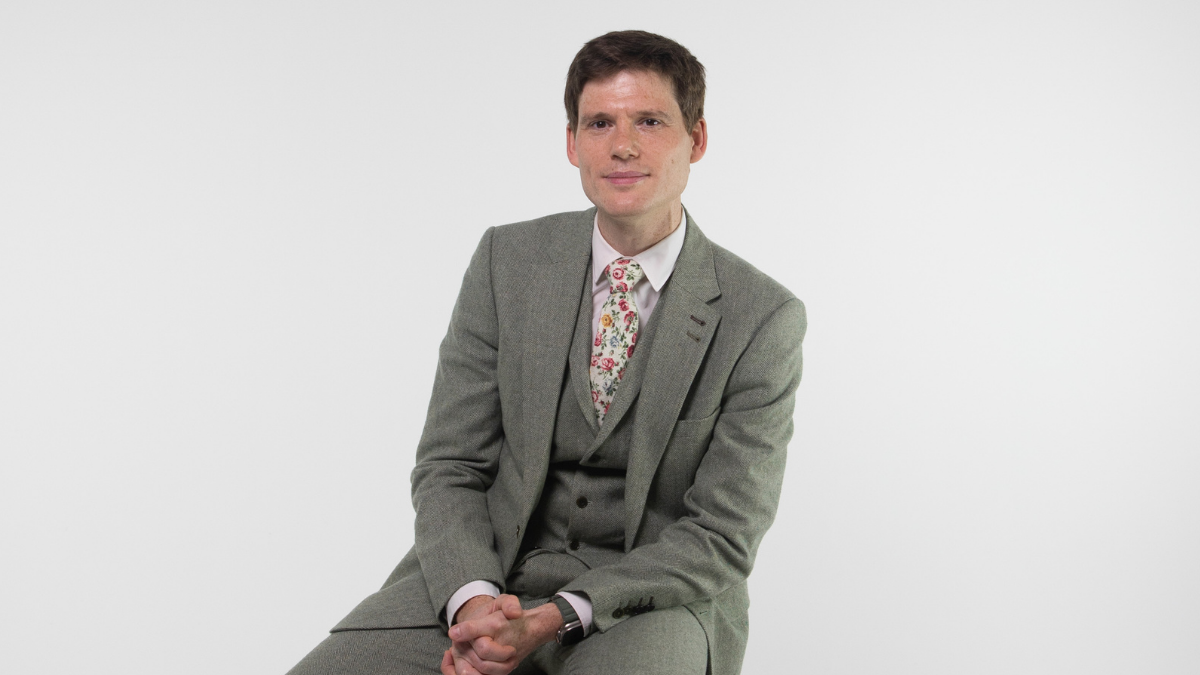 Professor David Clifton sits on a chair in the middle of a photography studio and smiles directly at the camera
