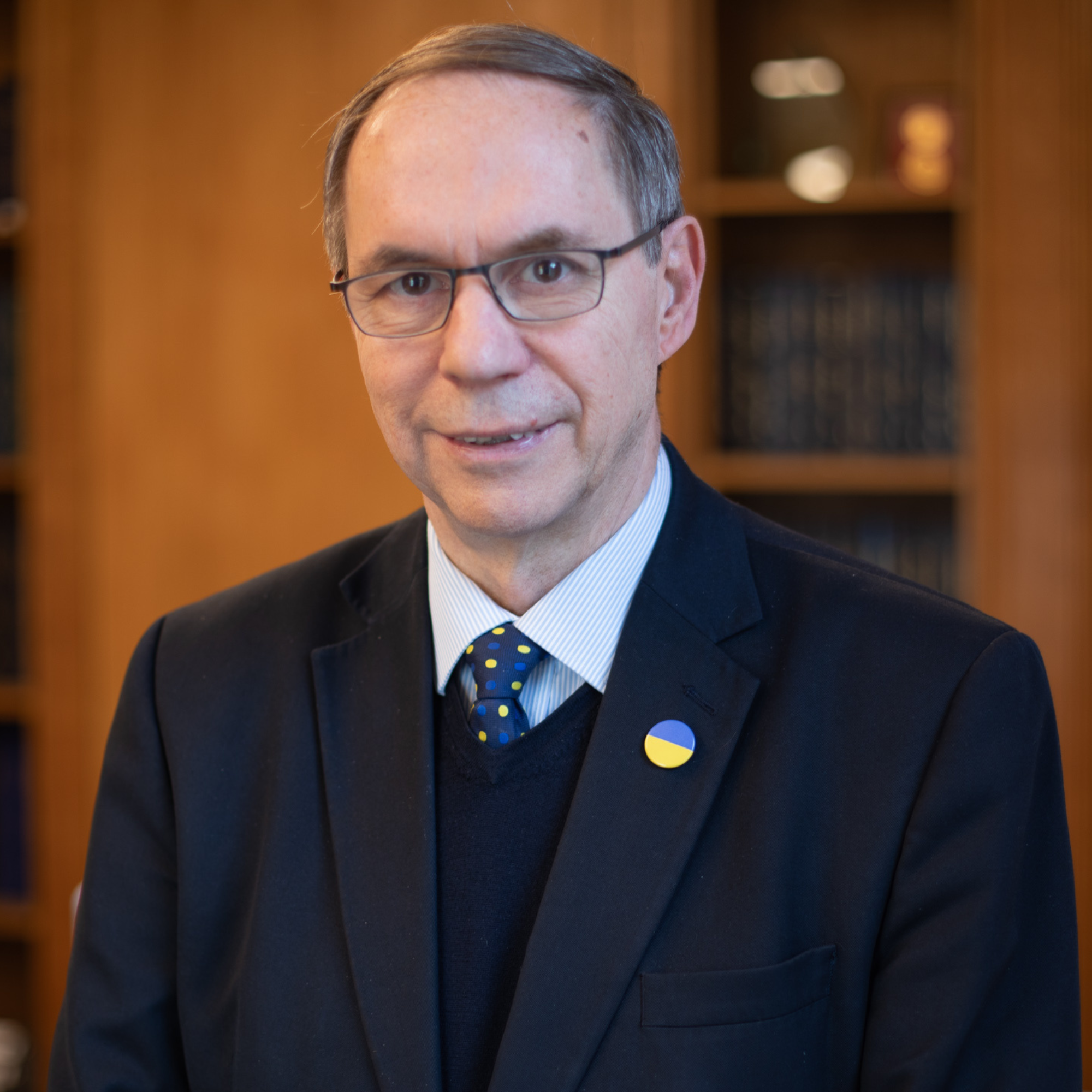 Professor Lionel Tarassenko, wearing a suit and Ukrainian flag lapel pin, looks into the camera,