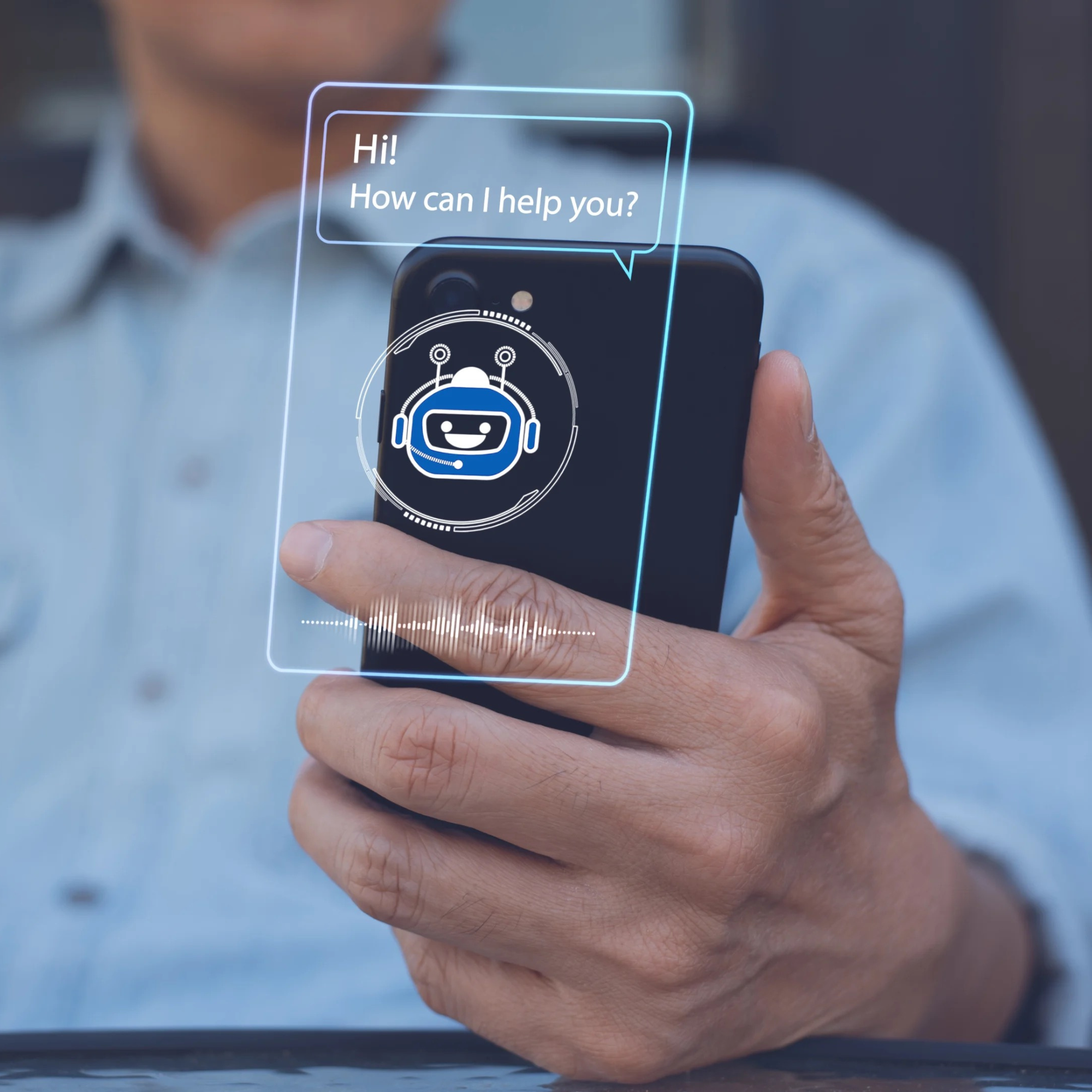 A person holds out a mobile phone with a projected pop up of a chat bot say 'Hi! How can I help you?'