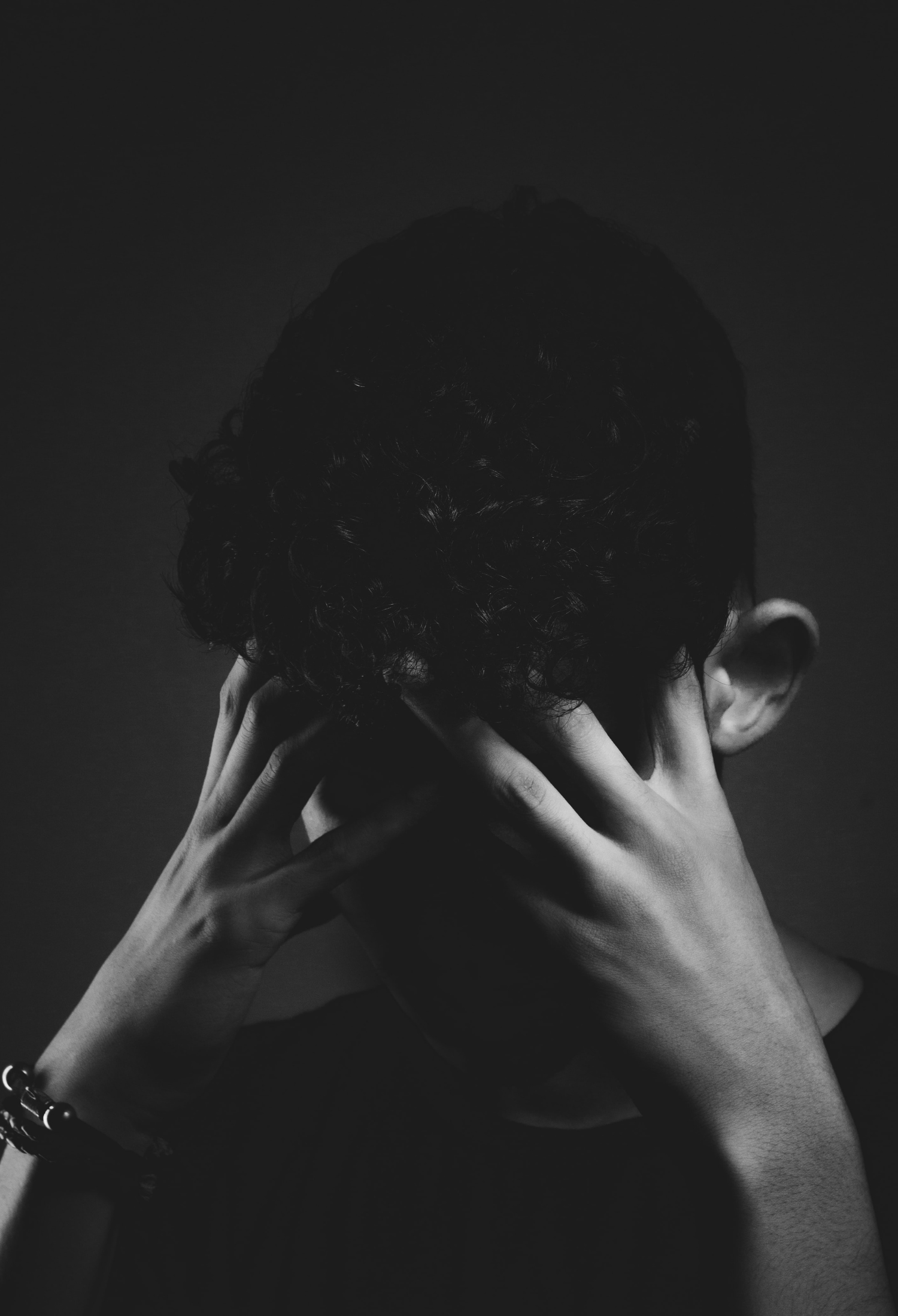 A teenager holds their head in their hands