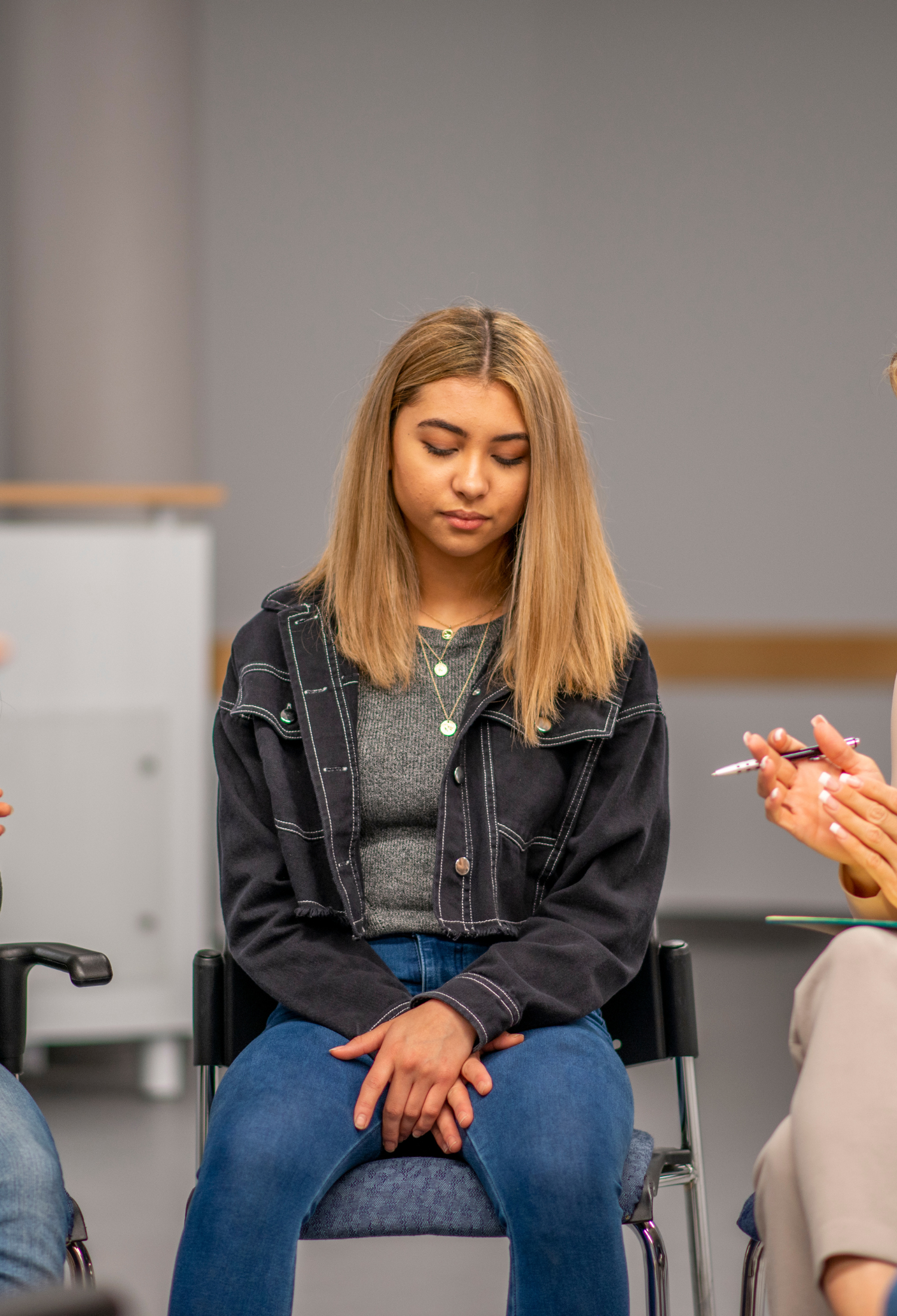 A teenager sits in a circle with others, talking to a therapist