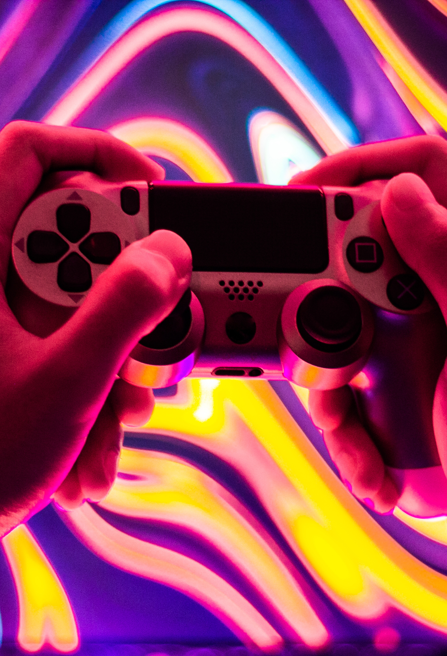 Someone holding a games controller in front of a vibrant colour background