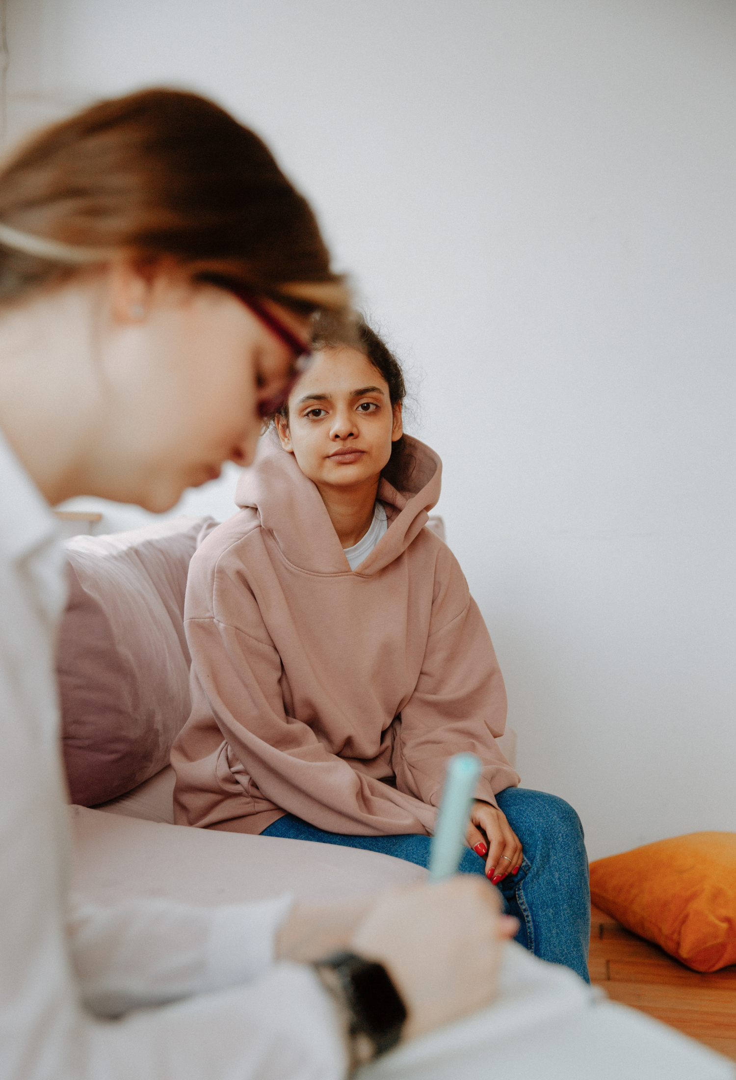 A young person looks with a blank expression at their therapist