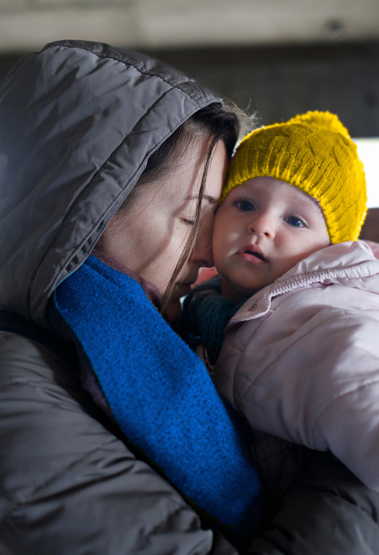 A woman in winter coat and scarf cradles a young child