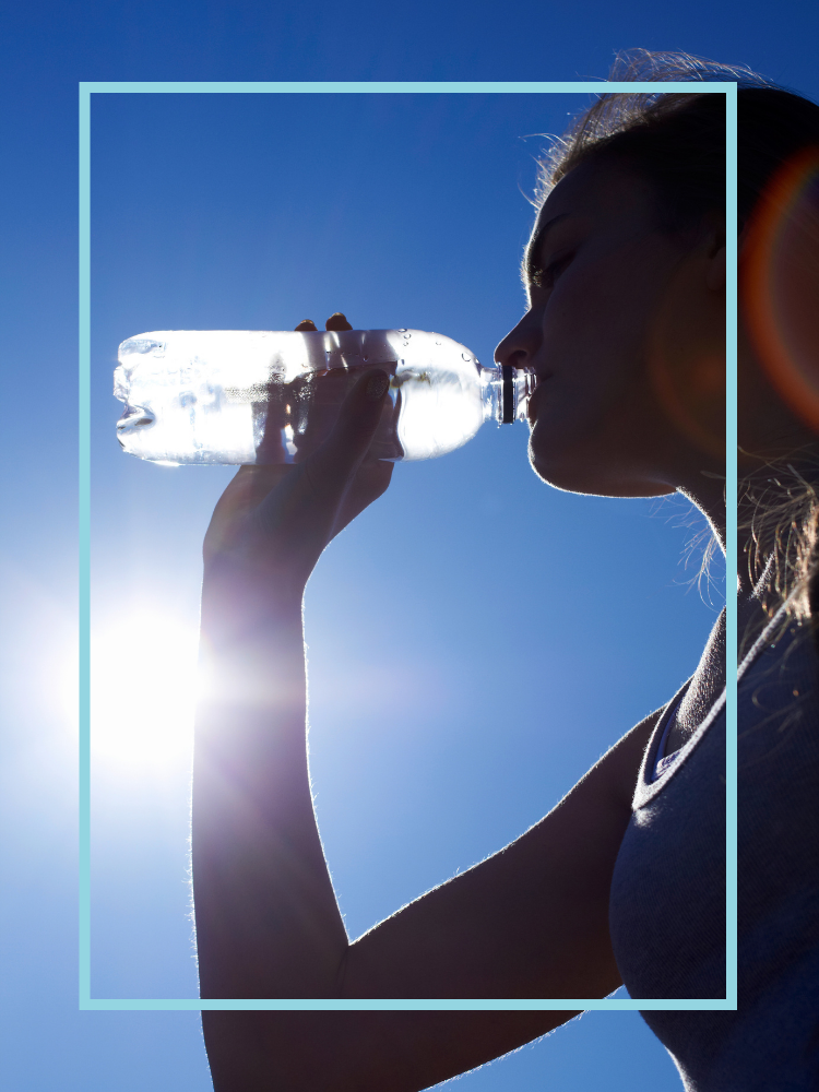 A woman drinking from a plastic water bottle