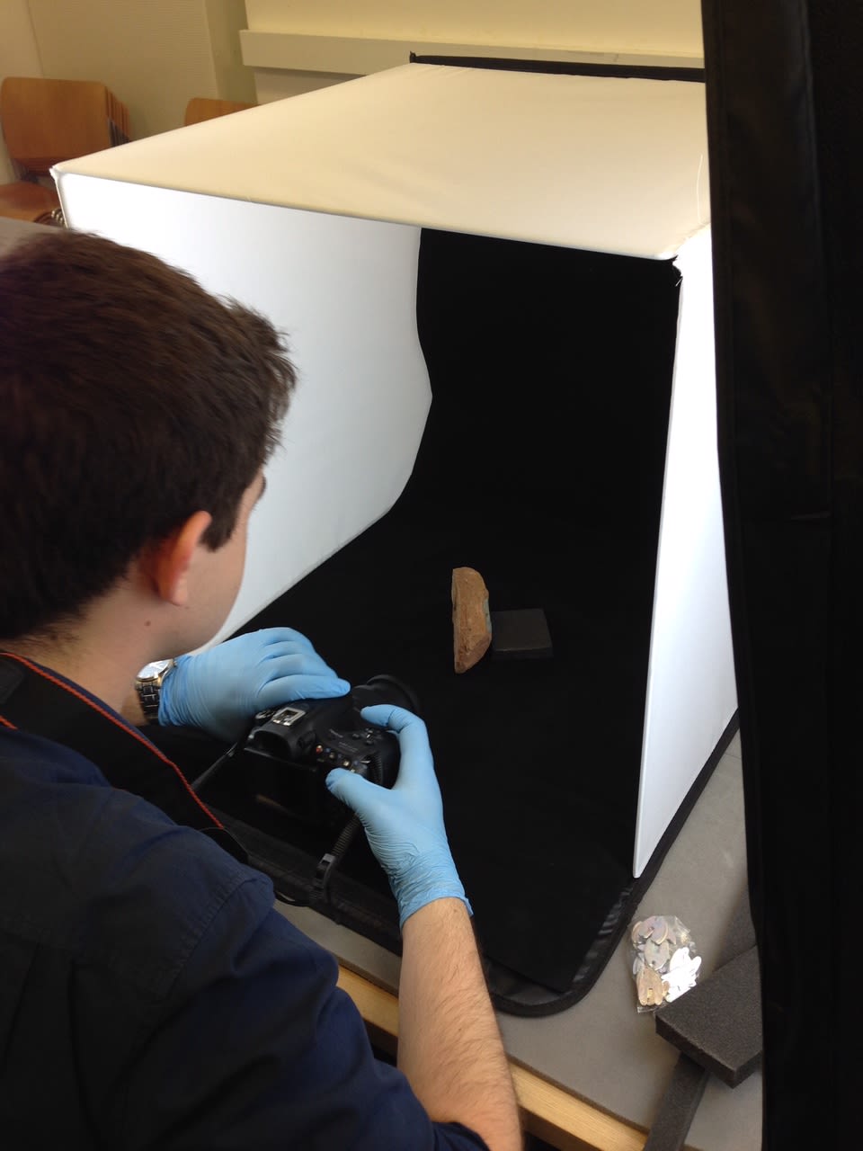 A man in gloves photographing a small object