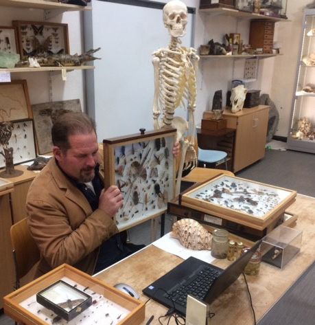 Academic holding up a display of insects while teaching