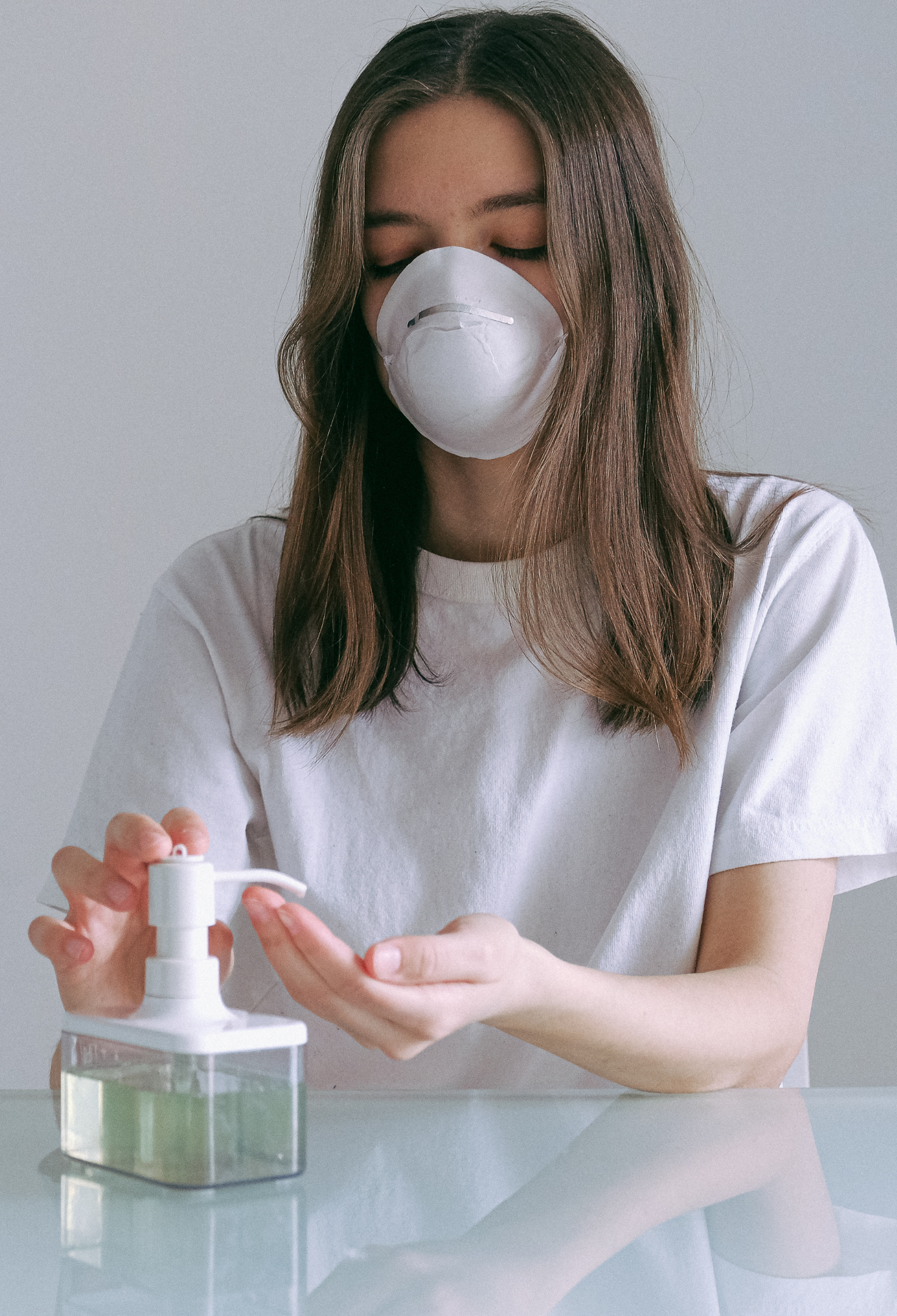 A woman wearing a face mask sanitises her hands