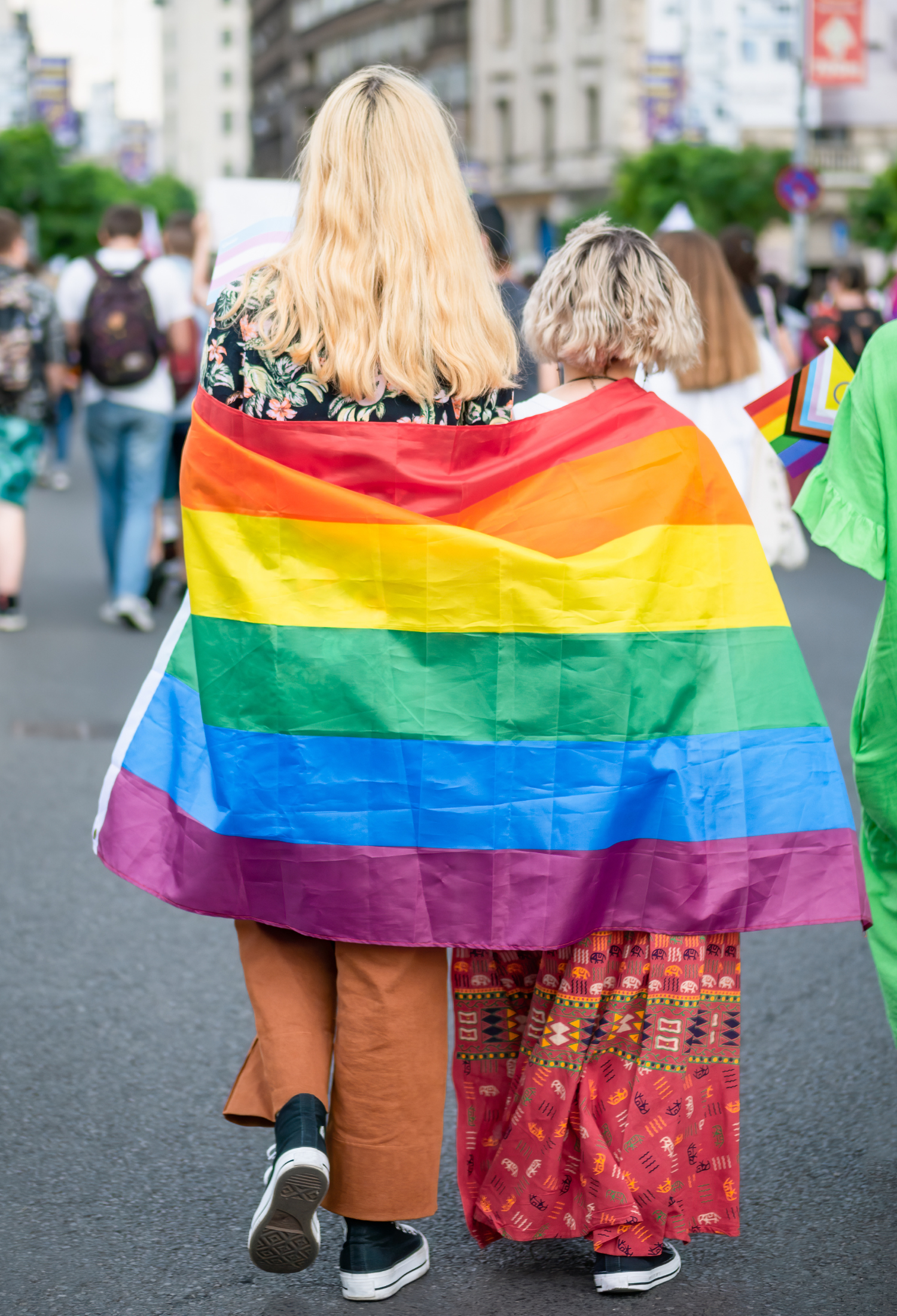 Two people draped in pride flags 