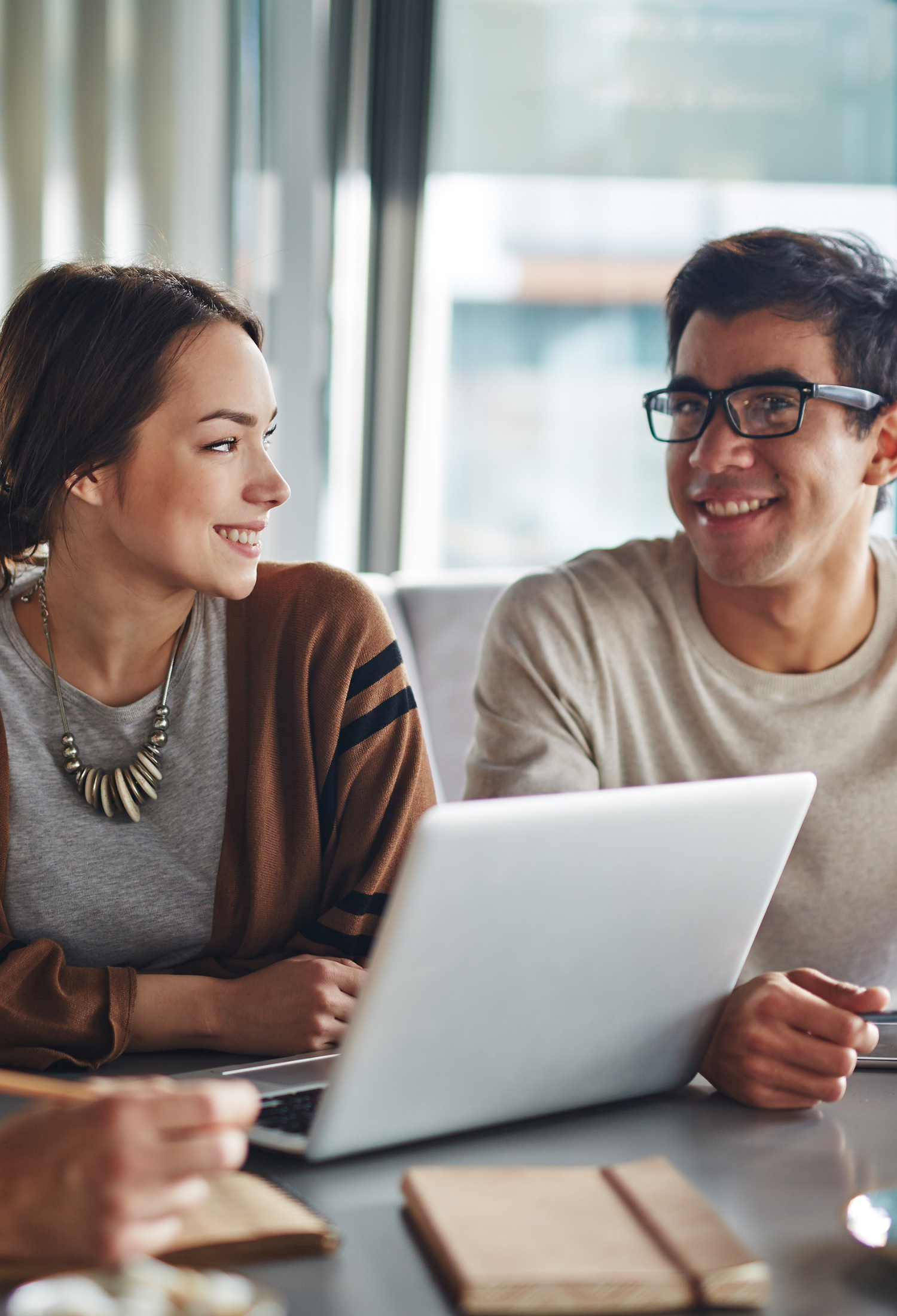 People facing each other and smiling with a laptop