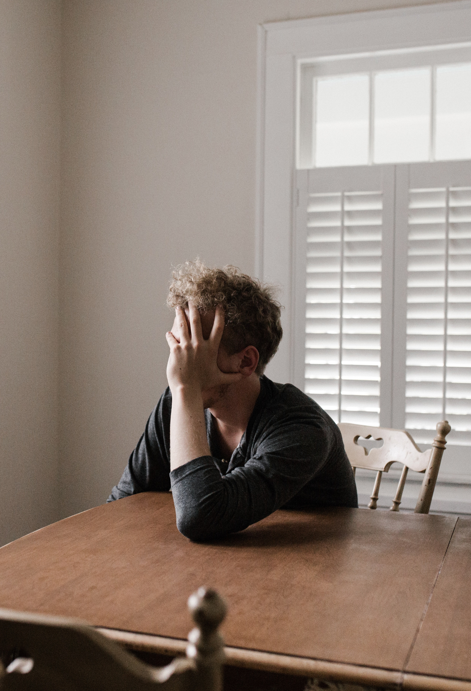 A man sitting alone at a table with his head in his hands