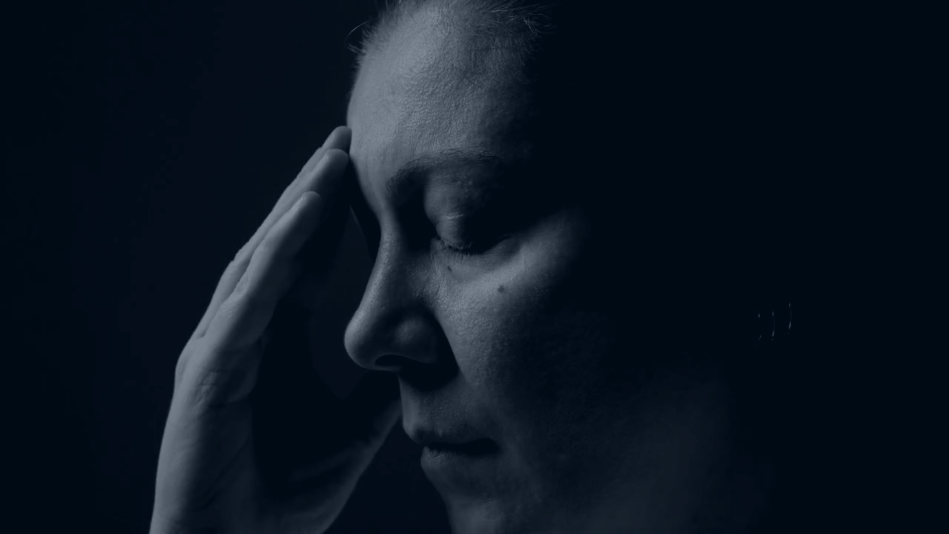 A parent holds their hand to their head and closes their eyes