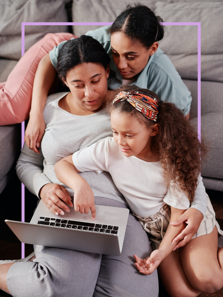 Two women and a girl looking at a laptop