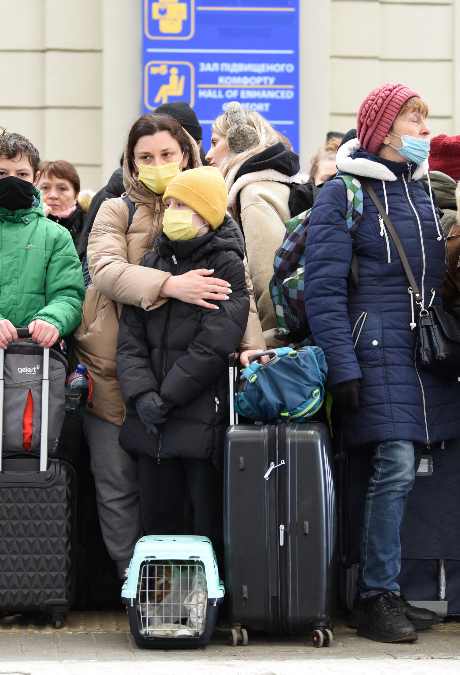 A woman and child on a train platform in masks and winter coats