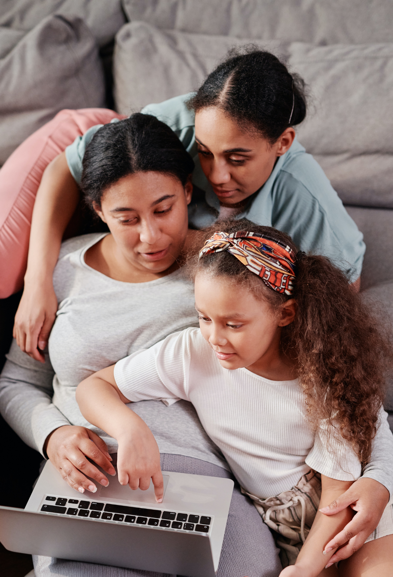 Two women and a girl looking at a laptop