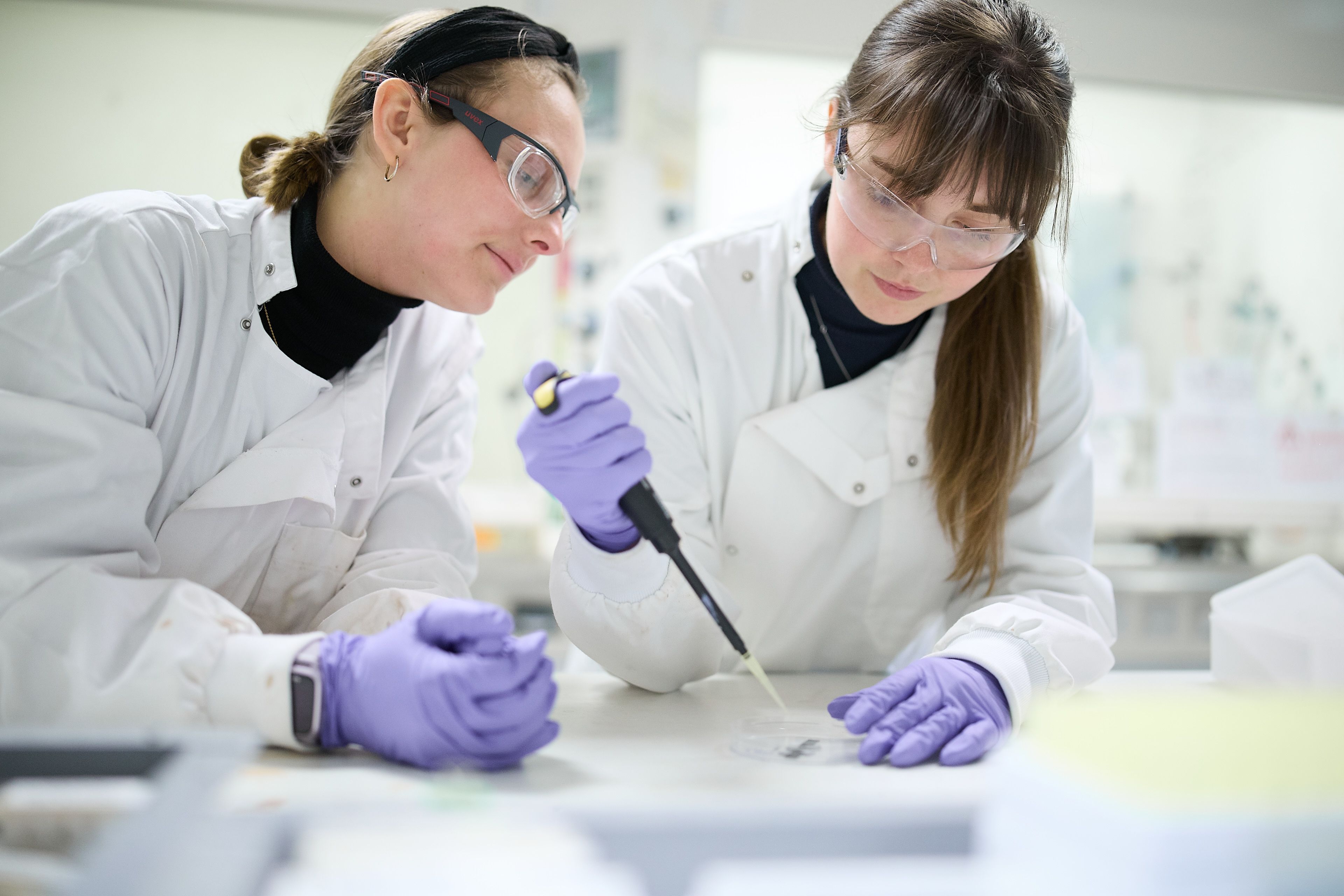 Phil students using a pipette in a laboratory