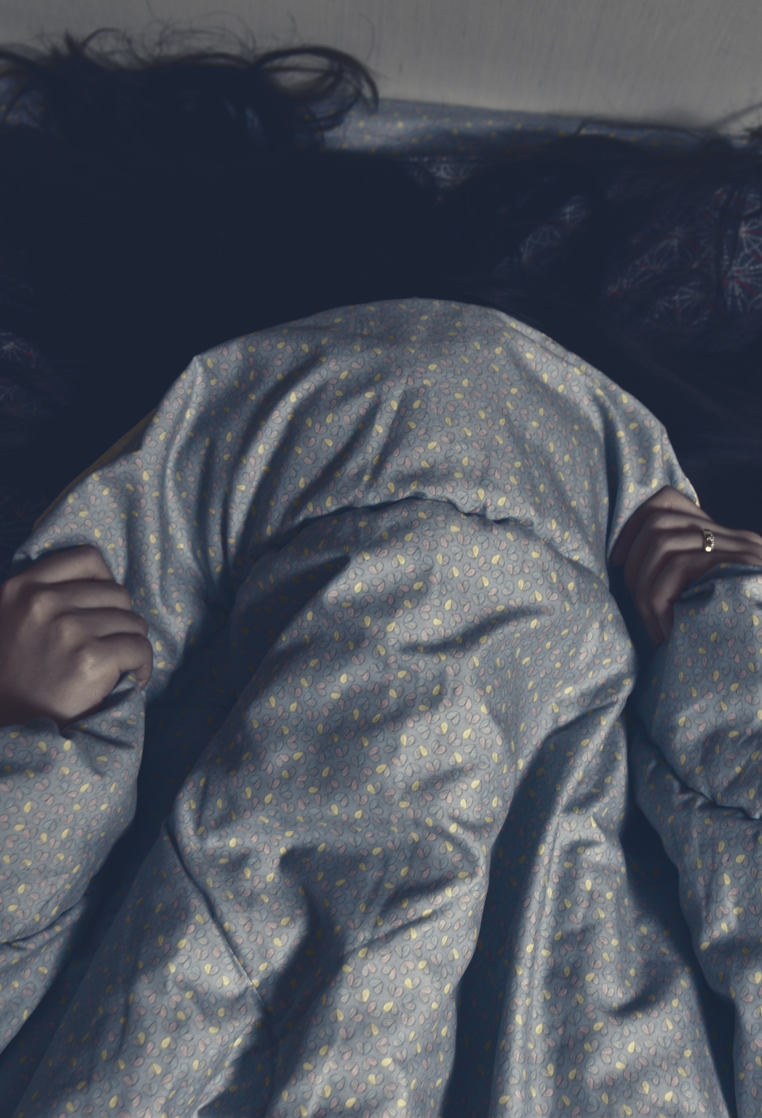Someone pulls their duvet over their head and grips the covers