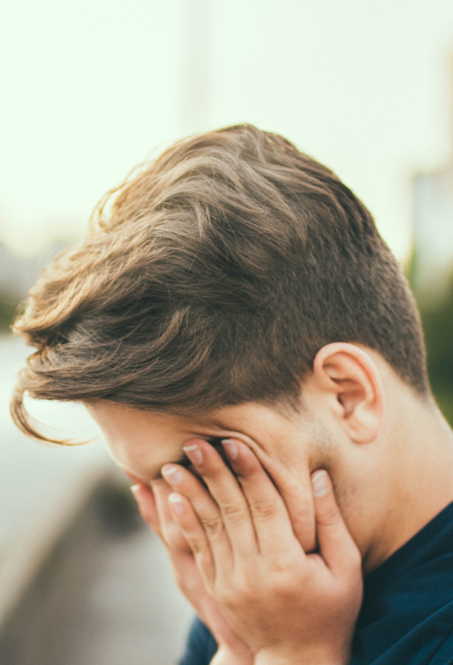 A teenage boy holds his head in his hands