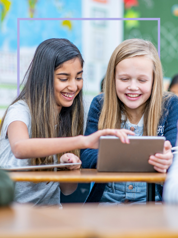 Two young girls using a tablet and smiling